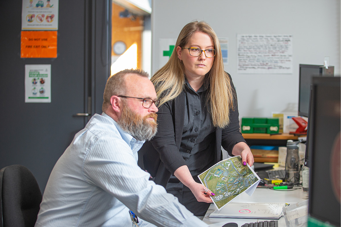 Two probation officers looking at a map together at their desks at Upper Hutt Community Corrections