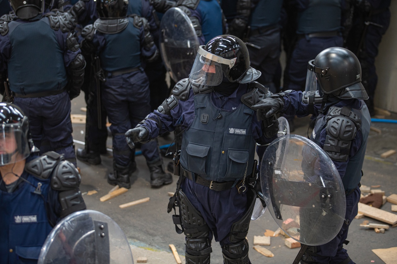 Corrections staff in protective gear crowding around